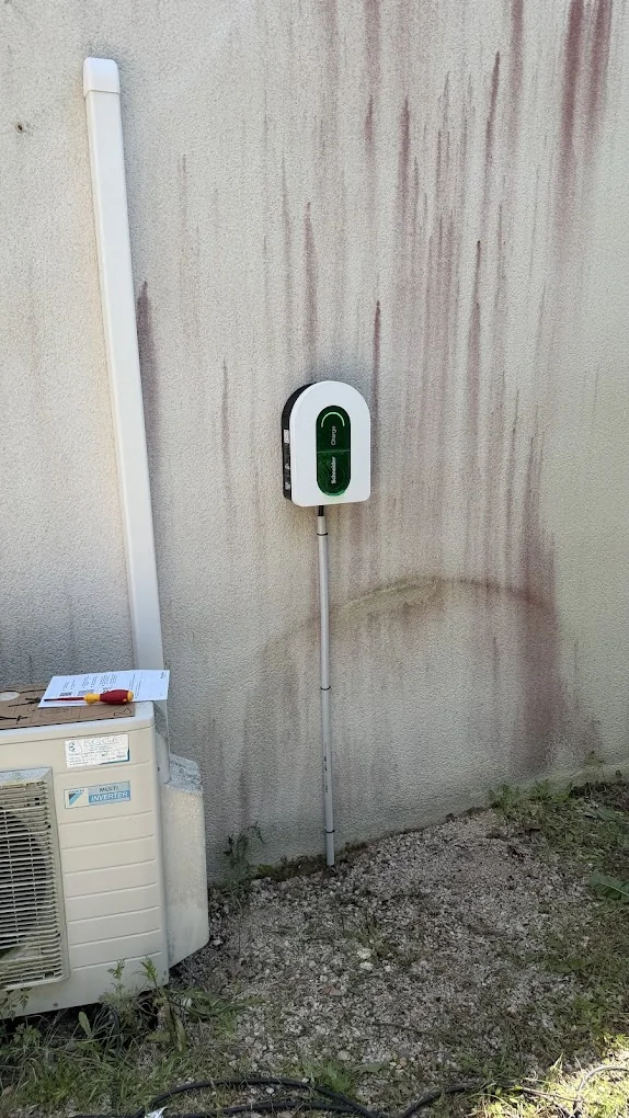 Borne de recharge pour véhicule électrique installée sur un mur extérieur