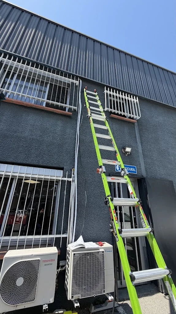 Intervention de climatisation avec échelle sur façade